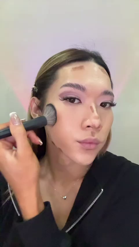 Maddie blending contour makeup with a brush for a seamless finish